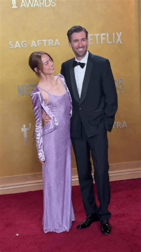 The ‘90s called—they want #EmmaStone’s @actorawards outfit back! The ‘Bugonia’ star arrives on the red carpet with her husband, #DaveMcCary. | ELLE Magazine (US)