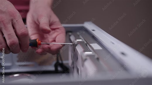 Closeup of technician hands using screwdriver to remove component from desktop computer case, concept of professional it service, maintenance, hardware upgrades. Shooting in slow motion.