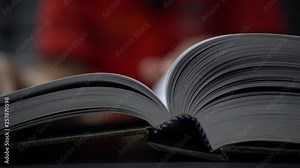 Old open book on desk in library. Hands holding fingers in page while reading. Research literature for learning education concept