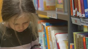 Little girl reading a book in a library - Free Stock Video