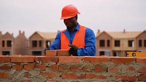 African American builder laying bricks at townhouse construction site