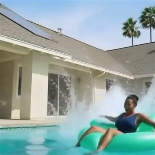 Yellow Lab jumping into a pool off of the roof splashing owner