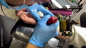 slow motion video of Professional tattoo artist making a tattoo on the hand, Close up of male tattoo artist making a tattoo on the hand to client