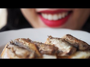 Girl eats Sprats (tiny fishes) with Bread. Mouth close up. Chewed food warning