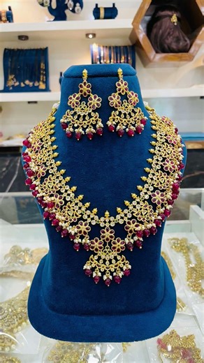 This traditional "Gutta Pusalu" necklace features a matte gold finish with ruby-toned stone accents