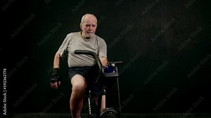 An old elderly man in sportswear is training in the gym doing weight lifting with dumbbells. Leisure healthy lifestyle. An elderly man is exercising. Fitness for the elderly. active pensioners.