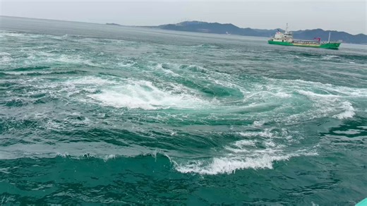 【日本地理ノート 171】鳴門海峡の渦潮は最大直径20メートルにもなる——これは異常気象ではなく、毎日規則正しく起き、事前に予測できる「潮位差の物理現象」だ。 ・成因：紀伊水道と播磨灘の潮位差が最大約1.5メートル、狭い海峡をくぐる流れが世界最大級の渦を生む ・見方：観光船で海面から迫力を体感、または大鳴門橋内の「渦の道」から真上で構造を観察——同じ渦が全く違って見える ・大塚国際美術館：橋のたもとに建つ、世界1,000点以上の名画を陶板原寸で再現した美術館───────────── ＊もっと詳しく＊──────────鳴門の渦潮の仕組みは明快だ。1日2回の満干潮で紀伊水道と播磨灘の潮位差が生まれ、大量の海水が鳴門海峡の狭いボトルネックを一気に通過する。最速で約15km/hに達する流れが海底地形と干渉し、渦を形成する。この現象は潮汐から正確に予測でき、観潮時刻表も公開されている。観光船では渦の音と揺れを体で感じられ、橋上の「渦の道」ではガラス床越しに渦の構造を真上から観察できる。同じ渦潮を全く異なる視点と身体感覚で体験できるのが鳴門の面白いところだ。大塚国際美術館は、崖に掘り込んだ空間
