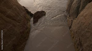 Tilt down from Elephant cove as waves roll in towards the passage between two boulders.