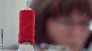 filmed close-up of coil with red threads and the wound gradually untangled when working with sewing machine Key