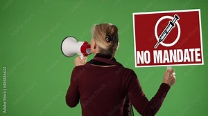 Woman holding sign and talking into megaphone protesting vaccine mandate on a green screen chroma key background.