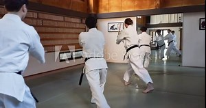 Aikido, group and fight class with sensei, weapon training and wooden sword for self defence exercise. Dojo, students and athlete in a gym or studio with workout, black belt practice and fitness