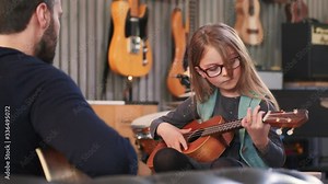Dad teaching guitar and ukulele to his daughter.Little girl learning guitar at home.Close up.Ukulele class at home. Child learning guitar from her father