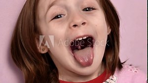 A cute little girl at a maxillofacial surgeon's appointment shows her throat. A wide open mouth sticks out a long tongue, a soft palate and saliva are visible. Focus on the soft palate.