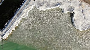 Charlevoix Michigan Pier Lighthouse overlooking Lake Michigan Great Lakes with Fresh Water on a Sunny Winter day with icebergs floating drone looking down at ice formations Stock Video