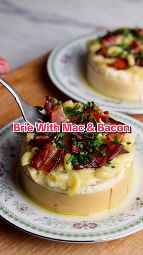 Next Up On Winter Warmers, Meals To Warm Your Bones On Cool Weather Days = Baked Brie With Mac & Bacon. Simple To Prepare & Simply Delicious! Full Recipe Below! Makes 2 Servings 8 strips bacon 2 tablespoons pure maple syrup 2 large wheels of Brie 1 tablespoon thyme leaves 1 tablespoon olive oil 150 grams dry macaroni 1 tablespoon butter 1/4 cup grated parm 2 tablespoons minced chives Sea salt & cracked black pepper Preheat your Traeger Grill to 375 degrees F. Line a baking sheet with parchment p