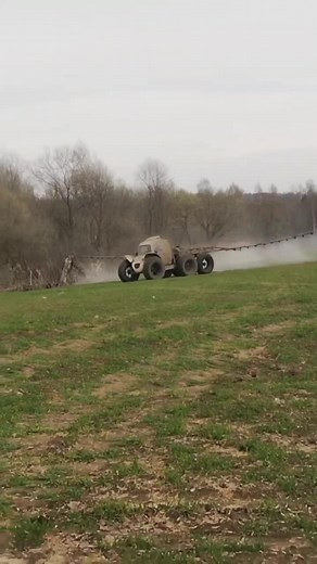 Off-Road Vehicle Spraying Mist Over Grassy Field