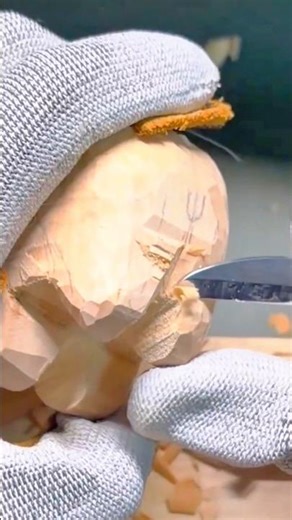 carving a detailed wooden figure using a sharp manual knife by a craftsman wearing protective