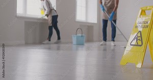 Cleaner group working, floor washing, yellow wet caution sign, professional janitor service busy completing cleaning tasks at home, office. Taking care of room, maintaining hygienic sanitary mopping
