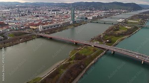 Cinematic Aerial View of Vienna: Danube River, Iconic Bridges, and Cityscape A stunning drone shot capturing Vienna's Danube River, its iconic bridges, and the city's scenic skyline from above.