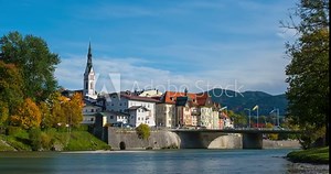 Timelapse of golden autumn in famous tourist landmark medieval town Bad Tolz. View of Isar river, trees, mountains, downtown and church. Bad Toelz, Bavaria, Germany. Camera zoom in