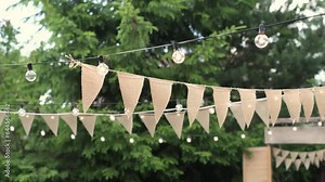 Transform Backyard into Dreamy Oasis: Discover how beige triangle flags and ambient light bulbs create whimsical garden setting perfect for evening soirees. masterclass in outdoor party elegance