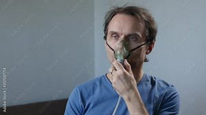 Adult sick man using nebulizer during inhalation therapy procedure