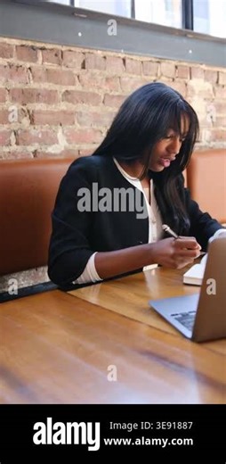 Young professional black woman typing on a computer and writing in a notebook at a modern workspace Stock Video Footage - Alamy