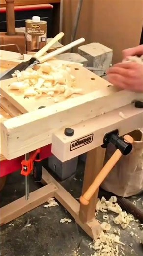 Cleaning wood shavings and chips from a workbench with hands to maintain tidy woodworking workspace