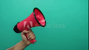 Hand holding pink megaphone against green background conveying communication and announcement concept.