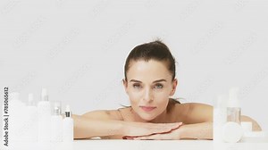 Advertising of spa treatments, anti-aging care products for delicate dry skin. Portrait of an attractive middle-aged woman next to mock-ups of jars of cream and cosmetology natural cosmetics.