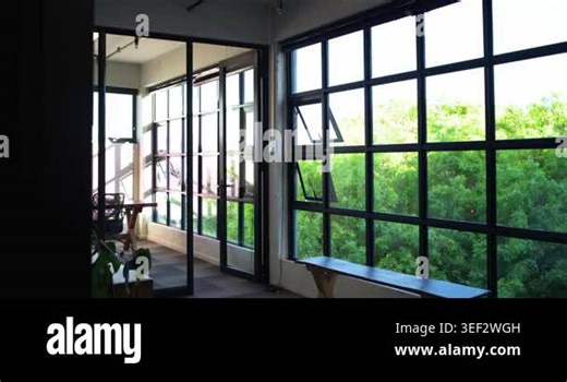 Camera is panning, revealing glass meeting room beside grid window to frame table and chairs. Partition, office, industrial, wooden, bench, plants, greenery Stock Video Footage - Alamy