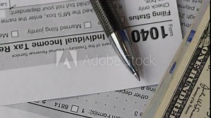 1040 tax return with pen and dollar bills rotation close-up. filling out tax returns for US citizens. tax payment topic