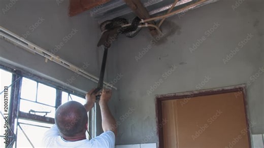 men carefully handle a massive African rock python From house Indoor Ceiling in a rural Botswana setting