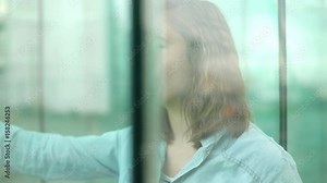 Woman looking through window with dreamy expression on face