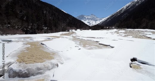 Camera at pavilion moving to show snow covered travertine pools and terraces in famous Huanglong scenic area, World Heritage site located in China's beautiful Sichuan province.