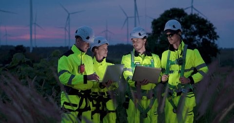 clip-4029040361-engineers-checking-laptop-data-during-dusk-wind