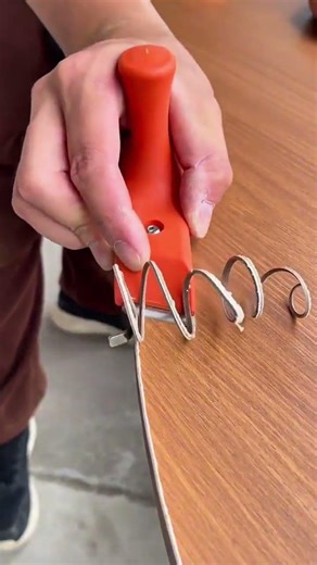 trimming excess edge banding material from the curved wooden board using a manual flush cutting tool