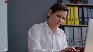 Senior woman works behind a laptop. Concept of remote work