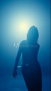 A mysterious silhouette of a woman dancing, highlighted by a moody blue backlight, showing elegance and motion, captured in artistic shade.
