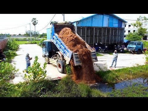Dump truck unload soil into the water and bulldozer pushing for level land