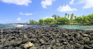Tropical rocky beach surf Pacific Ocean Hilo Hawaii pan. Big Island, largest, most volcanic active location. Economy is tourism based. Water and tropical beach recreation and fun.