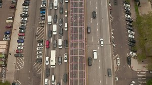 Top down overhead aerial view of pedestrians crossing Williamsburg bridge with dense rush hour traffic on the multi lane highway below