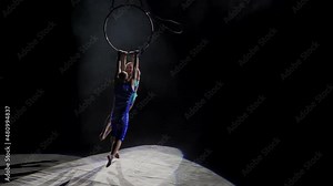 Aerial acrobat on the circus stage. A young girl and a guy perform acrobatic elements on the air ring, in the circus arena. Circus artists create shows for the audience. Flexible, athletic, aerialists