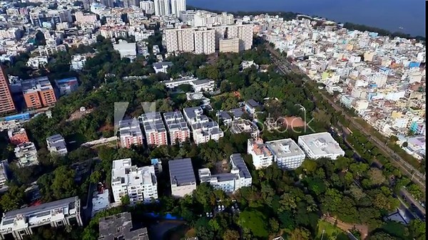 Wide aerial view of Hyderabad highlighting clusters of solar-powered rooftops, modern buildings, and lush green surroundings, reflecting renewable energy integration within a growing cityscape.