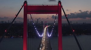 Epic Dolly forward through Istanbul Bosphorus Bridge Arch Illuminated in Red light at Night with Car traffic, Aerial Drone