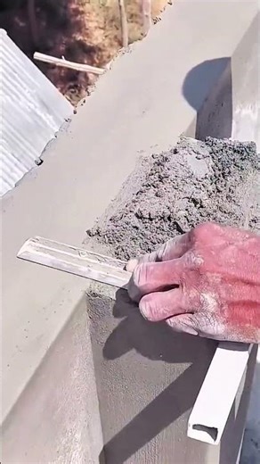 Leveling wet cement on wall edge with rectangular smoothing tool
