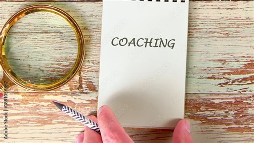 A person writes the word coaching on a small notepad from initial rough strokes to a finalized, neat presentation