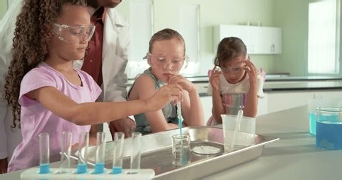 clip-4009244737-female-instructor-guiding-3-youth-girls-pipetting