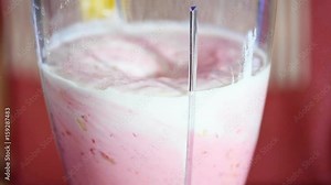 Woman using a blender for making a strawberry smoothie