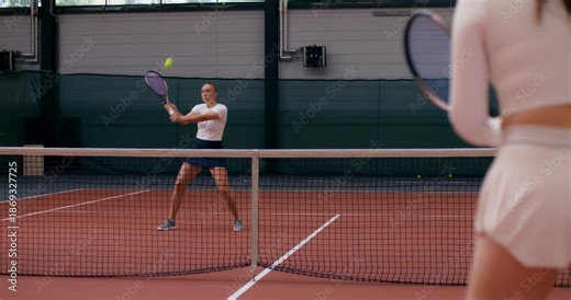 Two girls playing tennis on a court. Two female tennis players play a training match on the court.
